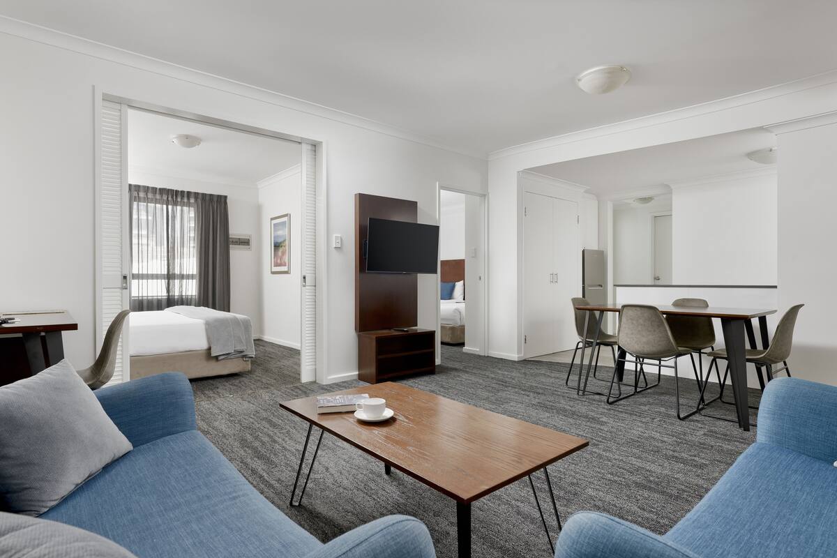 A hotel room with a bed, a TV, a dining area with chairs and a table, and a sofa.