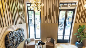 A modern interior with a sofa, two armchairs, a small table, a decorative wall piece, a hanging light fixture, and a potted plant. - AHC Taksim Hotel (Istanbul)