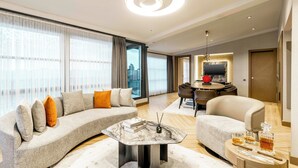 A modern living room with a curved sofa, a marble coffee table, and a dining area with a round table and chairs. - AHC Taksim Hotel (Istanbul)