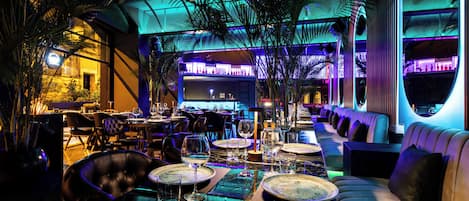 Un restaurante con un amplio comedor, varias mesas y un bar al fondo.