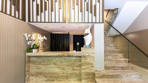 A reception area with a marble counter, a decorative sculpture, and a staircase with a glass railing. - AHC Taksim Hotel (Istanbul)