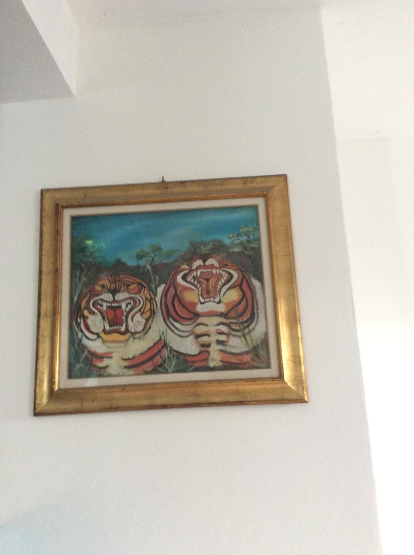 Un cuadro enmarcados de dos tigres sobre una pared blanca.