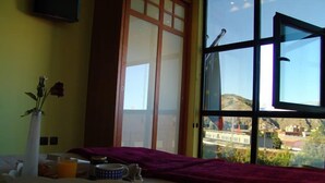 A room with a large window, a vase with flowers, and a tray with a teapot and cups. - Hostal Buenavista (Cuenca)