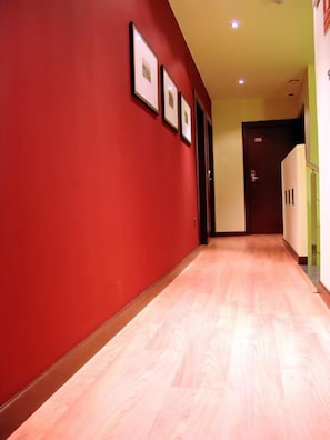A hallway with red walls and wooden flooring, leading to a door with a number sign. - Hostal Buenavista (Cuenca)