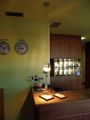 A hotel reception area with two wall clocks, a wooden counter, and a cabinet with numbered drawers. - Hostal Buenavista (Cuenca)