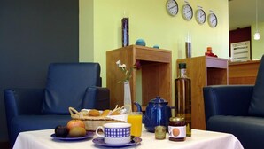 A breakfast setup with a table, chairs, and a clock on the wall. - Hostal Buenavista (Cuenca)