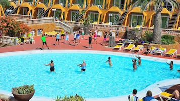 A swimming pool area with multiple sun loungers and a poolside bar.