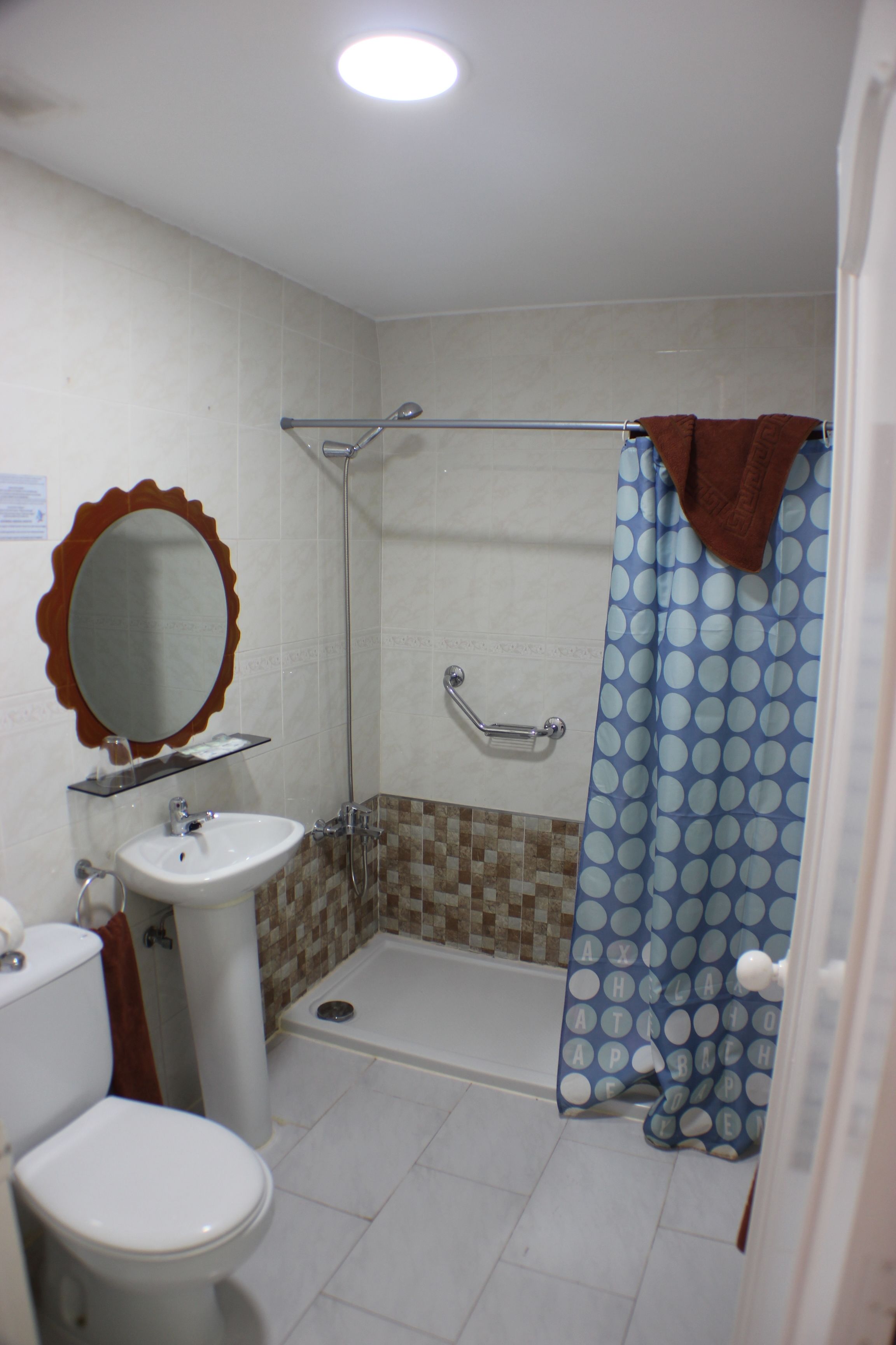 Un baño con inodoro, lavamanos, ducha y espejo.