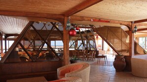 Interior de madera con muebles de mimbre, una escalera y vistas amplias por las ventanas.