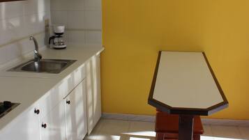 A kitchen with a sink, a coffee maker, and a table.