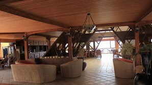 Un vestíbulo amplio con mobiliario de mimbre, una zona de bar y una escalera que conduce a plantas superiores.