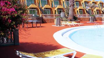 A pool area with sun loungers and a palm tree.