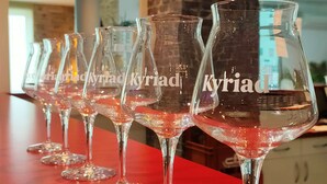 A row of empty wine glasses on a red table in a room with a brick wall and a ceiling with recessed lighting. - Kyriad Saint Chely d'Apcher - Aire de la Lozère (Albaret-Sainte-Marie)