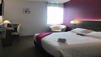 A hotel room with a bed, a desk, a chair, and a window.