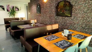 Een restaurant met bakstenen muren, houten tafels en zitjes.