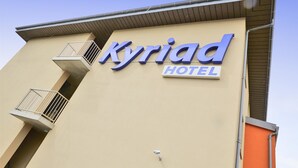 A hotel sign with the name "Kyriad Hotel" in large blue letters on a beige building facade. - Kyriad Saint Chely d'Apcher - Aire de la Lozère (Albaret-Sainte-Marie)