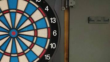 A dartboard mounted on a wooden stand against a brick wall.