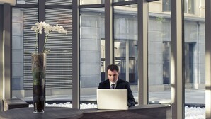 Ein moderner Empfangstresen mit einem Laptop, einer Blumenvase und einer außergewöhnlichen Deckenleuchte.