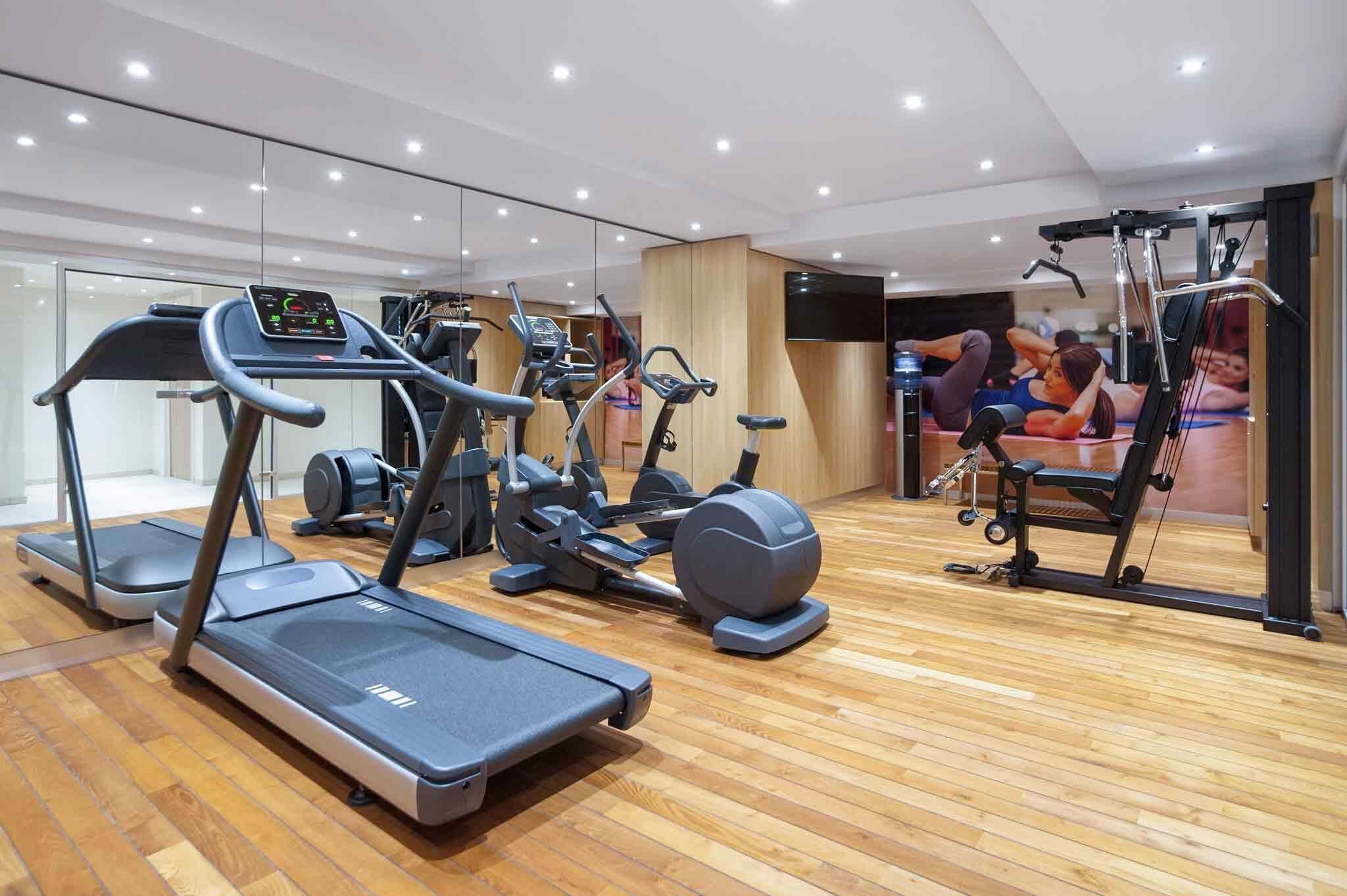 Een moderne sportschool met loopbanden, elliptische trainers en een roeimachine.