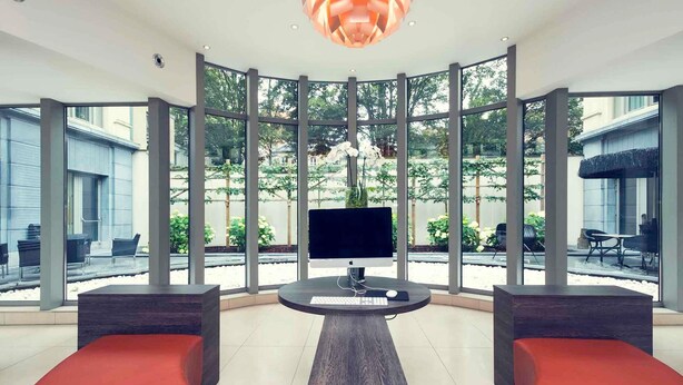 Ein modernes Interieur mit einem zentralen Schreibtisch, großen Fenstern und Blick ins Freie.