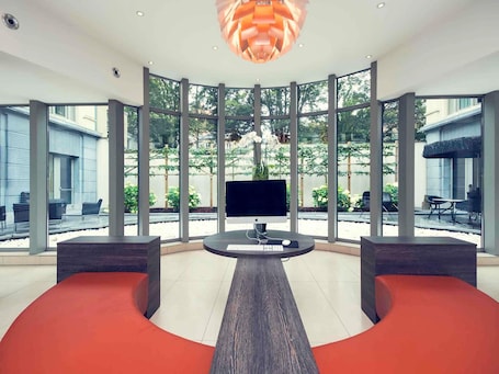 A modern interior with a central desk, large windows, and a view of the outdoors.. Mercure Brussels Centre Midi