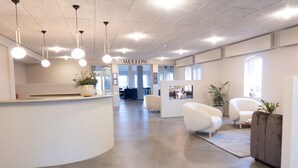 A modern reception area with a curved counter, multiple seating options, and a visible "AELLOW" sign. - HotelVFjorden (Lemvig)