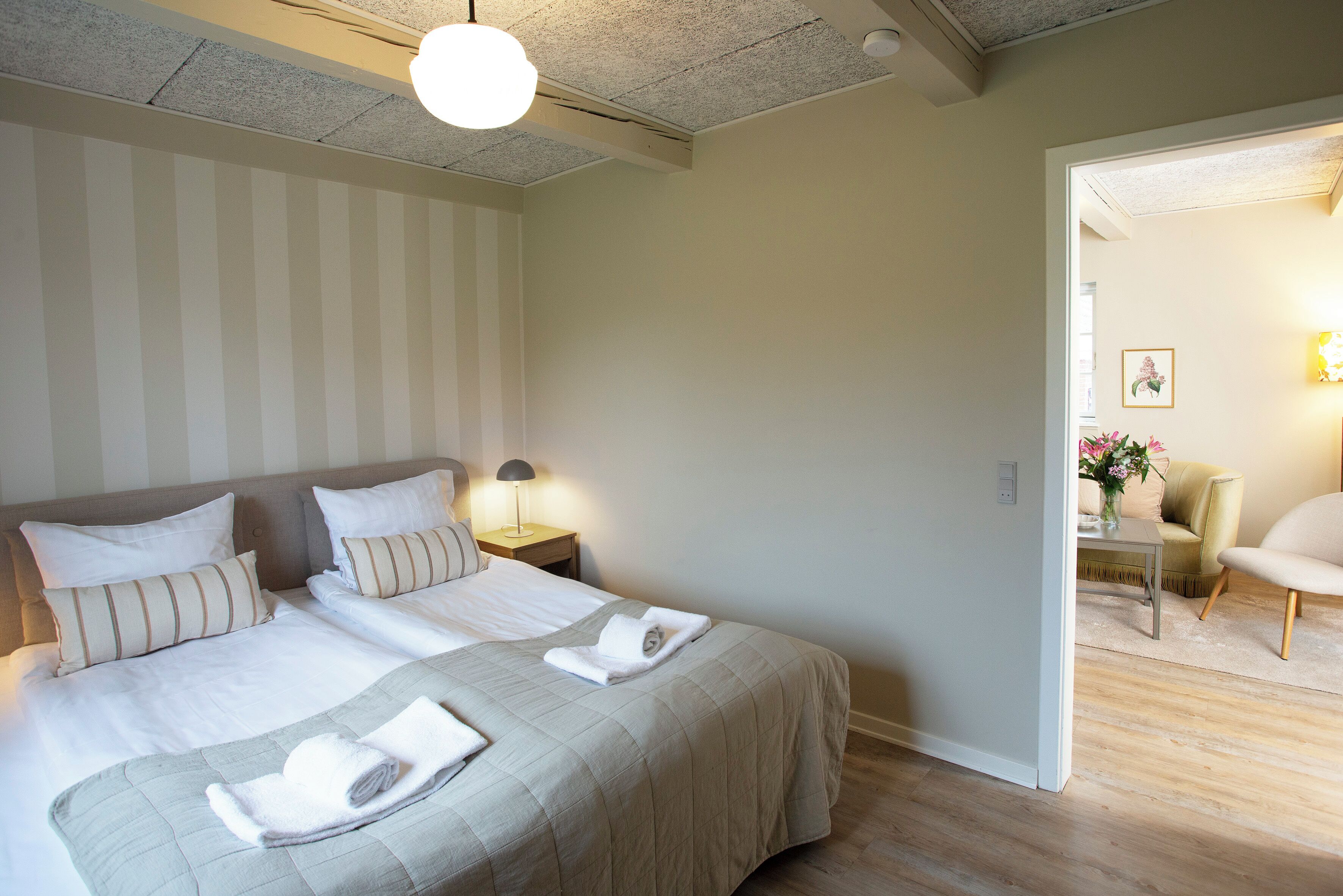 Una habitación de hotel con dos camas, una mesita de noche, una lámpara y una silla.