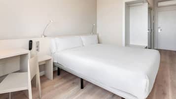 Un dormitorio con cama, escritorio y silla.