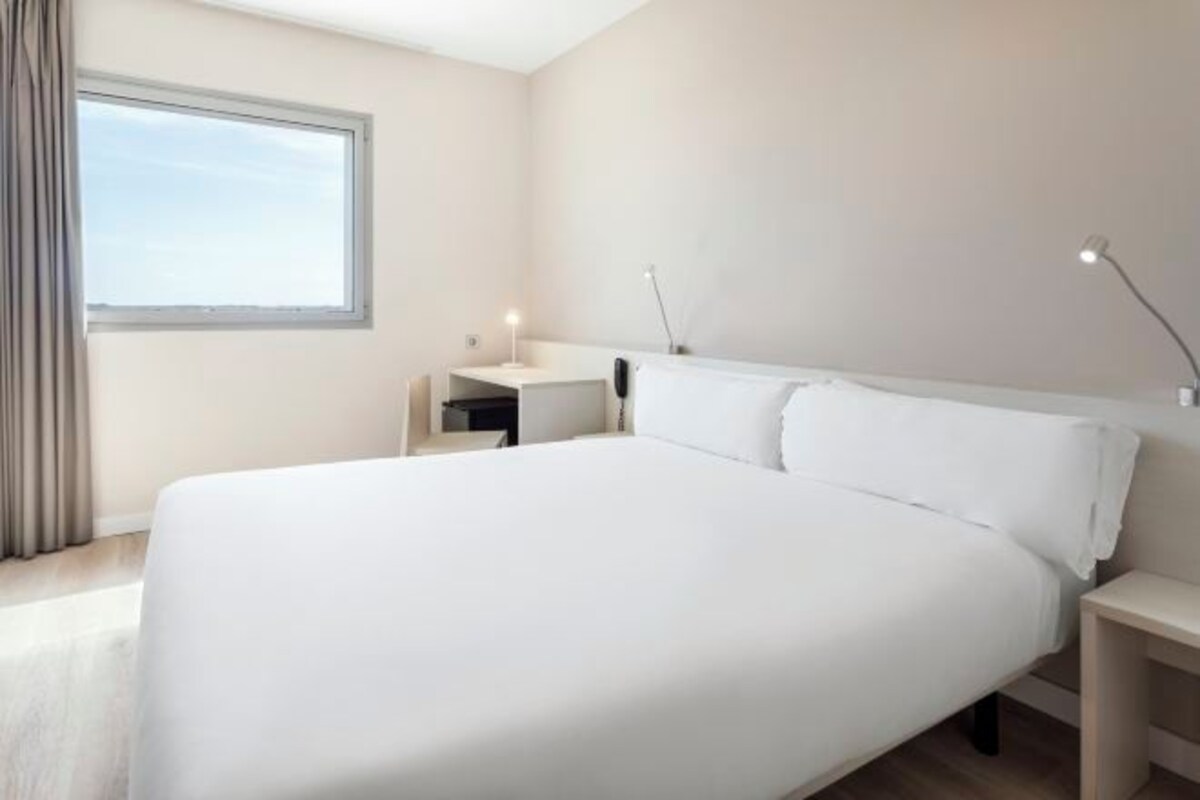Een moderne hotelkamer met een groot bed, een bureau en een raam.