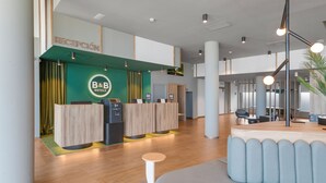 Ein Hotel-Empfangsbereich mit grüner Wand, einer Rezeption und einer Sitzecke.