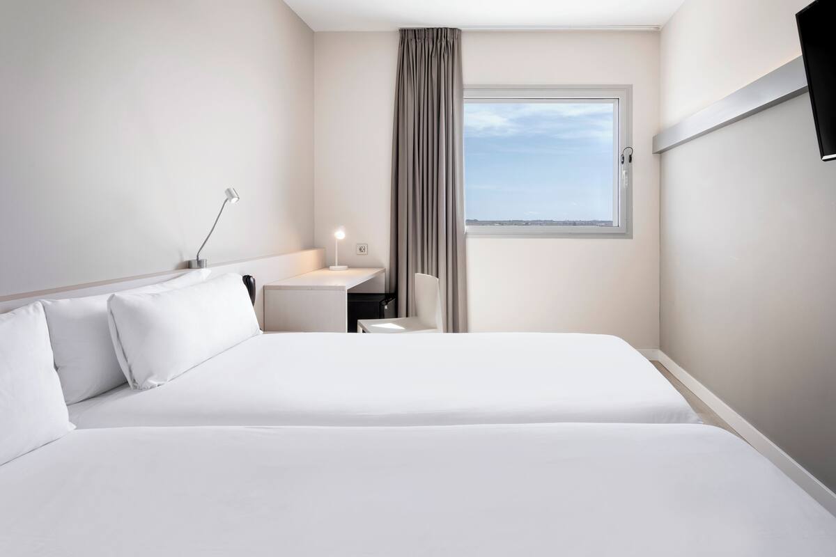 Habitación de hotel con una cama grande, un escritorio, una silla, un televisor y una ventana con vistas.