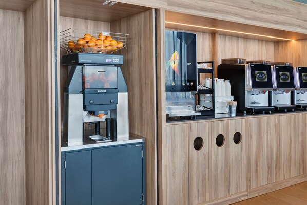 Una estación autoservicio de bebidas con una máquina de café y varios dispensadores.