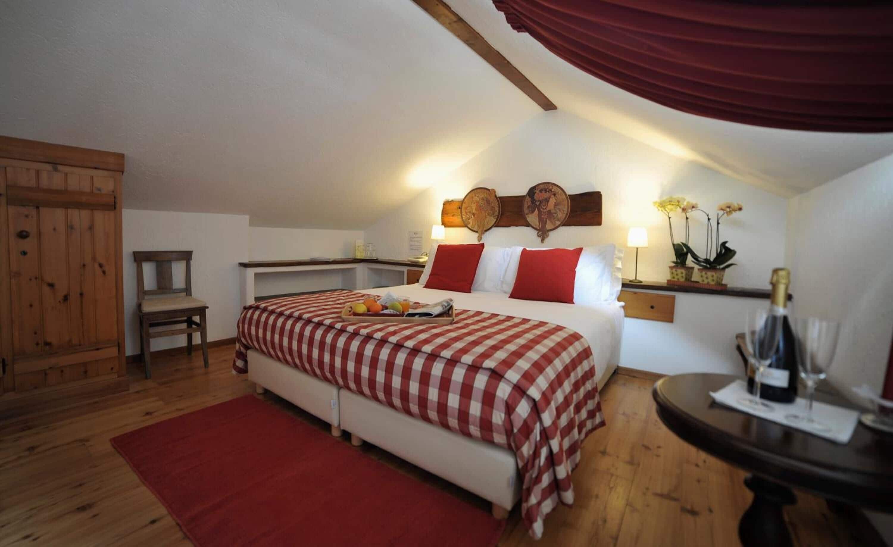 Ein Schlafzimmer mit einem Bett, einem Schreibtisch, einem Stuhl, einem roten Teppich und einem Holzkasten.