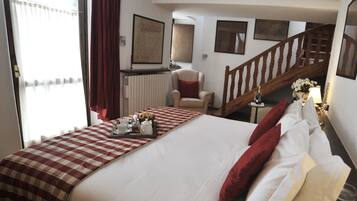 Habitación de hotel con una cama grande, una silla, una escalera de madera y vistas al exterior.