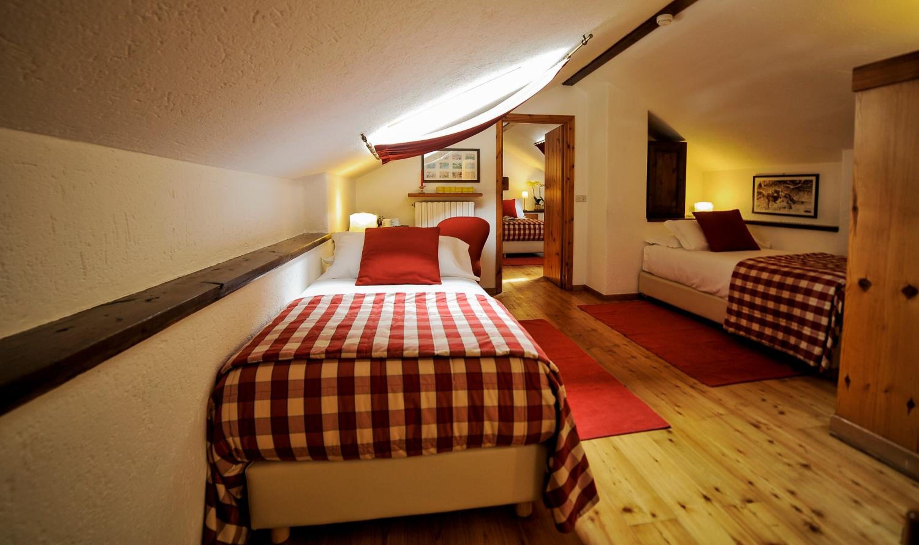 A bedroom with a large bed, a smaller sofa, and a wooden wardrobe.