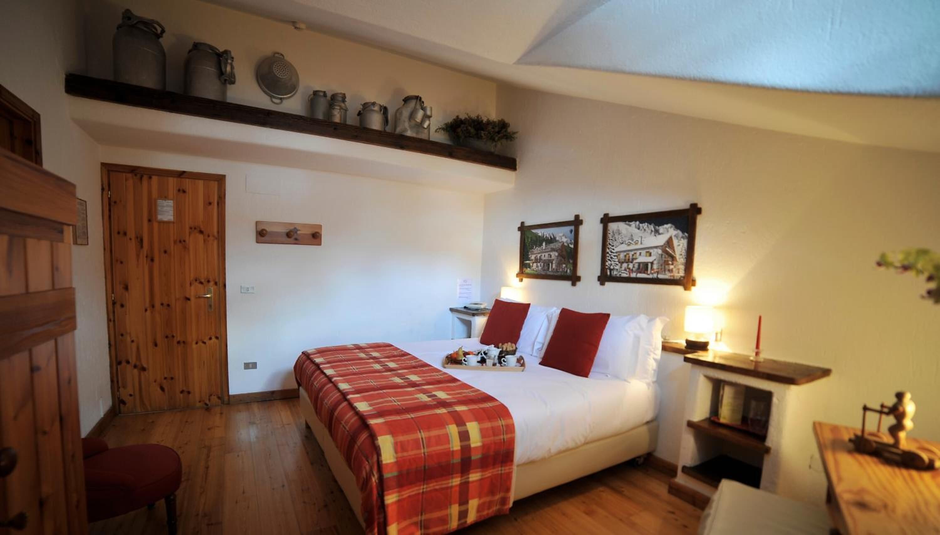 A cozy bedroom with a bed, a wooden door, and a shelf with kitchen utensils.