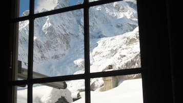 Une vue sur des montagnes enneigées, depuis une fenêtre.