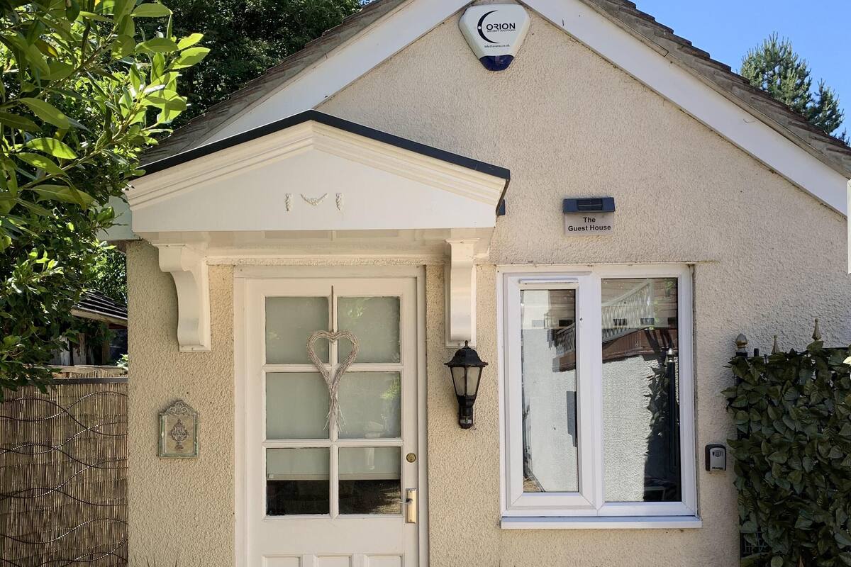 A guest house with a white door, a small window, and a sign reading "The Guest House".