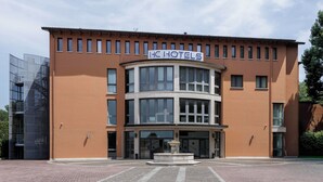 A hotel with a curved facade, large windows, and a central entrance with a fountain. - HC Hotel Cremona Pilgrim's (Cicognolo)