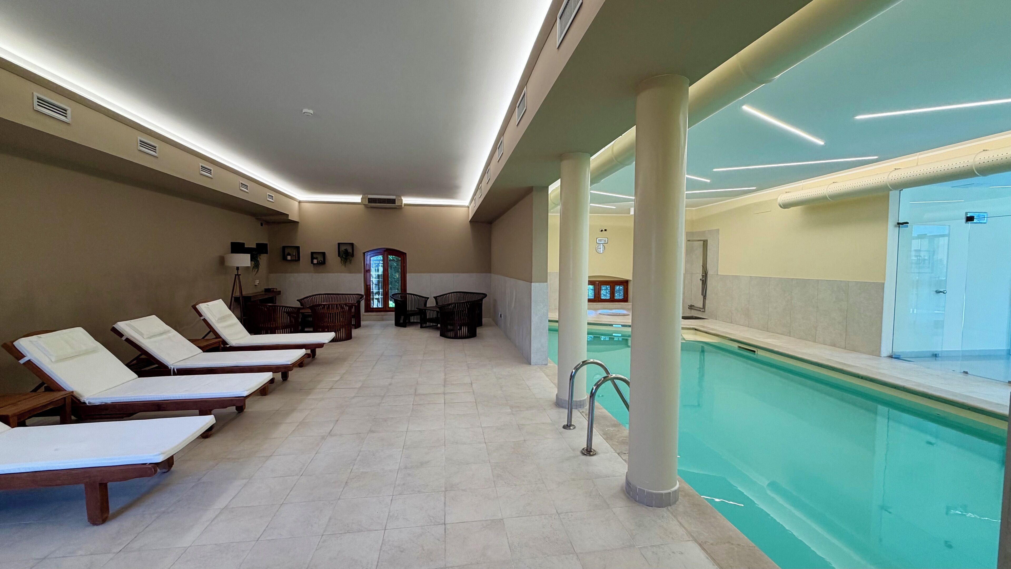 Zona de piscina con sillas de descanso, vestuarios y vistas a la piscina.