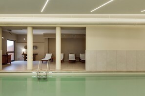 A pool area with a diving board, lounge chairs, and a reception desk. - HC Hotel Cremona Pilgrim's (Cicognolo)