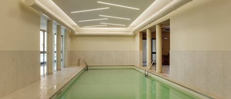 A swimming pool with a modern ceiling design, tiled walls, and a clear view of the adjacent room.