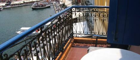A balcony with a view of a harbor, a table, and a railing.
