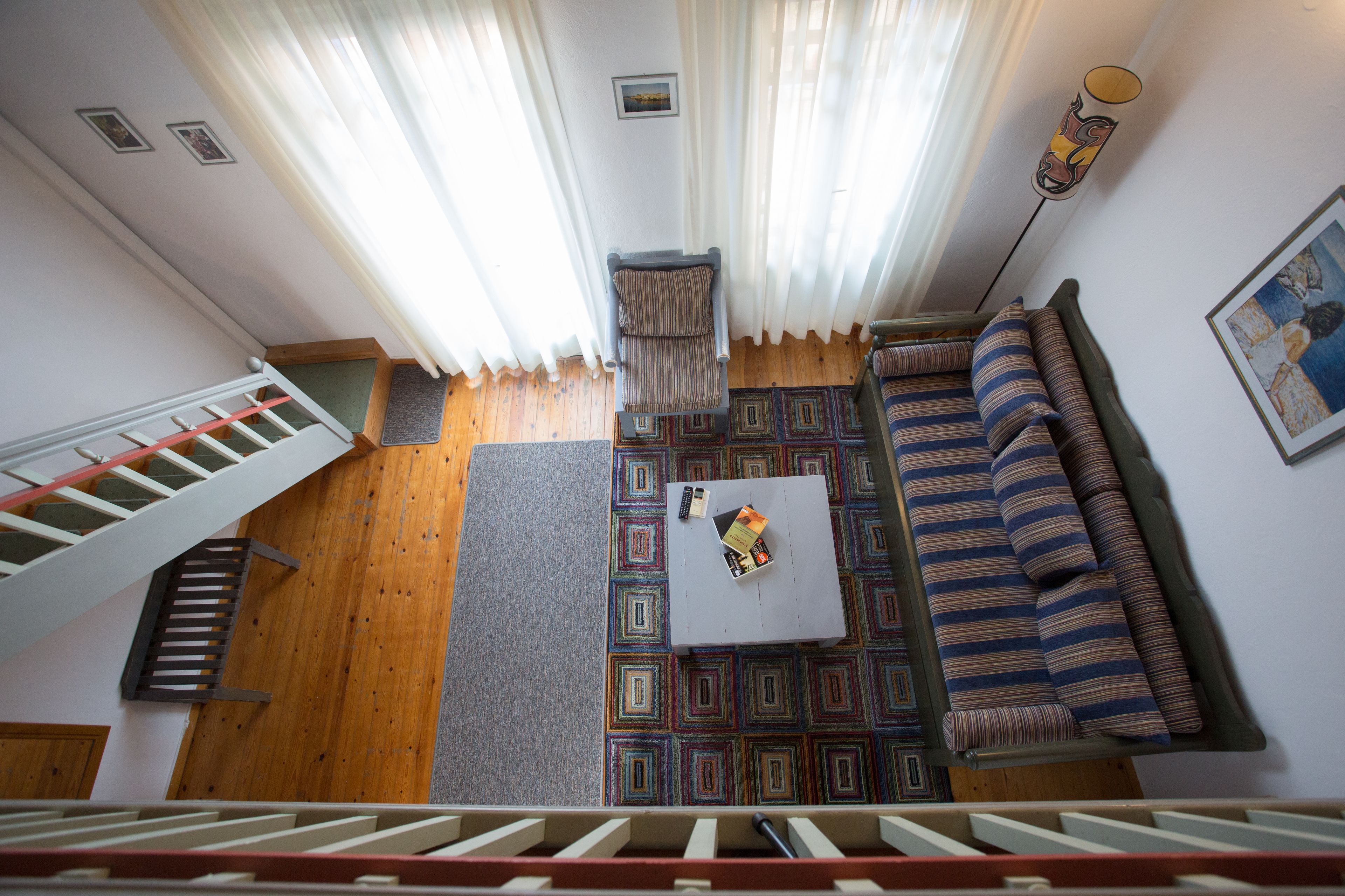 Une pièce avec un escalier, un canapé, une table basse et un tapis à motifs.