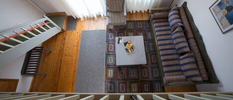 A room with a staircase, a sofa, a coffee table, and a patterned rug.