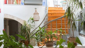 Una escalera con plantas en macetas, barandilla de madera y lámpara colgante.