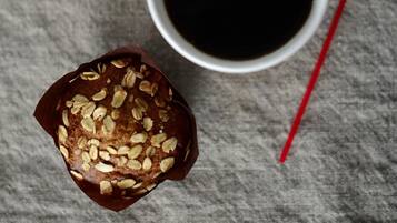 A loaf of bread with seeds and a cup of black coffee on a textured surface.
