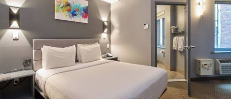 A modern hotel room with a large bed, bedside lamps, a painting on the wall, and a view of the outside through a window.