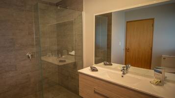 Une salle de bain moderne avec une douche à parois de verre, un grand miroir et un meuble-lavabo en bois.
