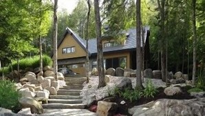 Una escalera de piedra que conduce a una casa rodeada de rocas y árboles.